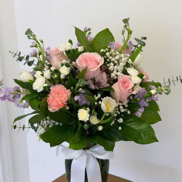 Pink and white mixed bouquet in a glass vase with a white ribbon