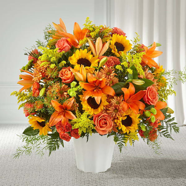 Orange and yellow mixed flower arrangement in a white vase
