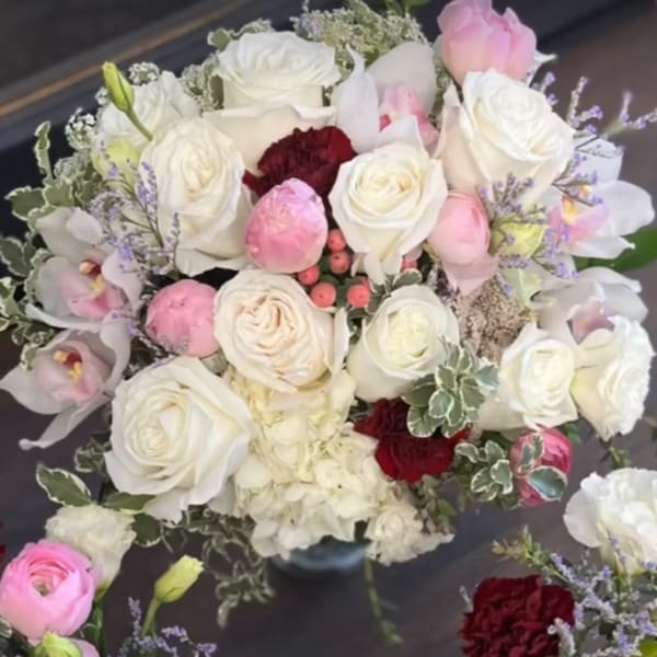Bouquet of white and pink roses with orchids in a vase
