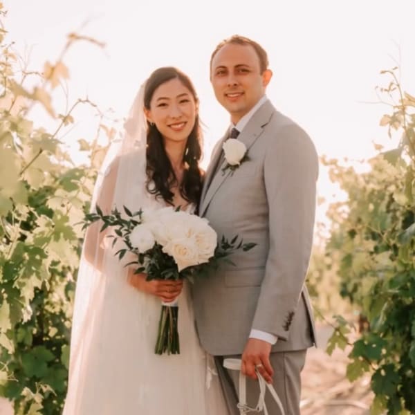Bride and groom holding a white bridal bouquet outdoors