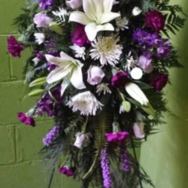 Tall standing floral spray with white lilies and purple flowers