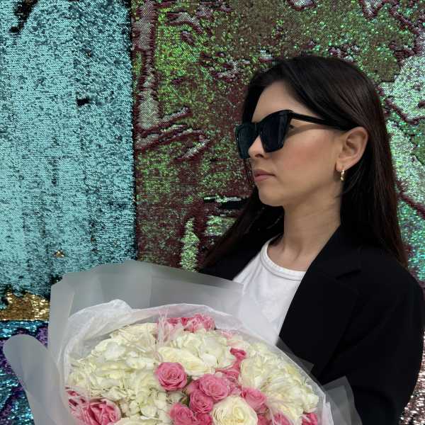 Woman holding a bouquet of pink and white flowers wrapped in translucent paper
