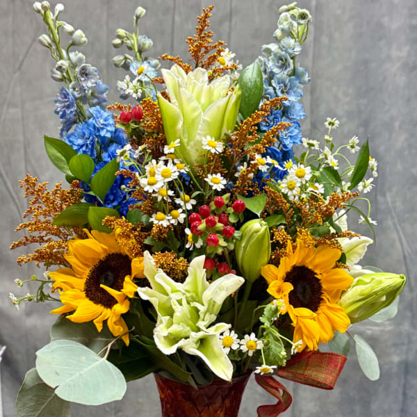 Colorful bouquet with sunflowers, lilies, and blue flowers in a vase