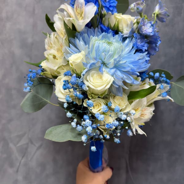 Handheld bouquet of blue and white flowers with a blue ribbon wrap