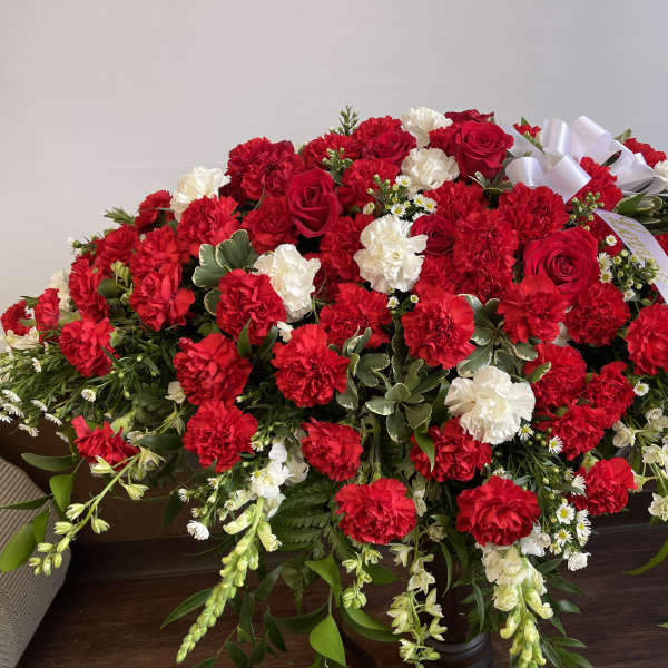 Large red and white floral casket spray with ribbon