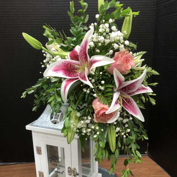 Pink lilies and roses arranged in a white lantern vase