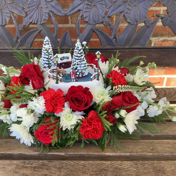 Red and white floral arrangement with a winter village centerpiece
