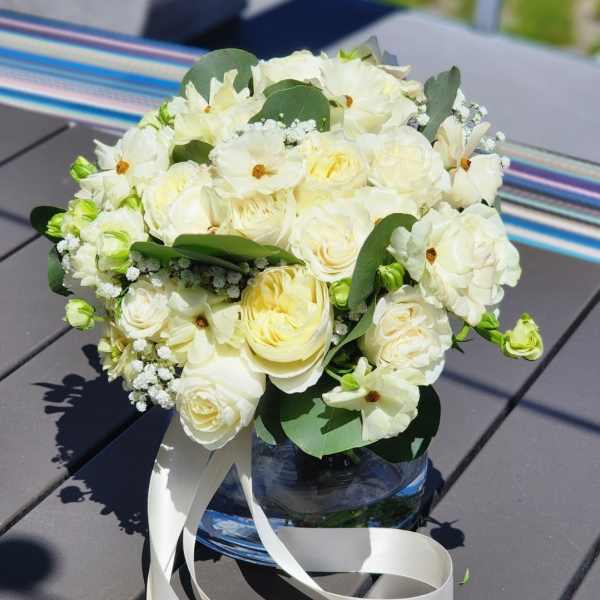 White floral bouquet in a glass vase with a white ribbon