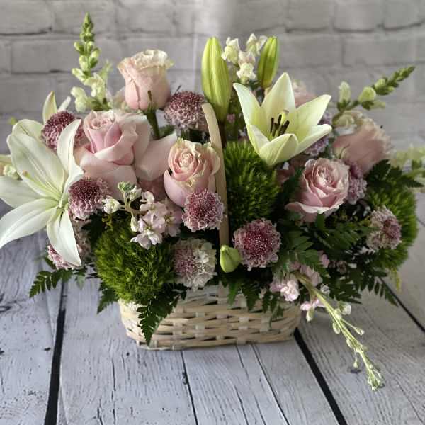 Pink roses and white lilies arranged in a wicker basket