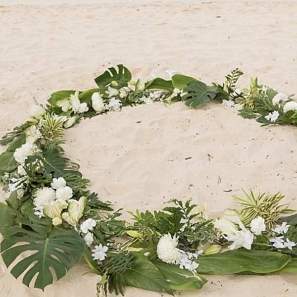 White floral wreath with tropical leaves arranged in a circle