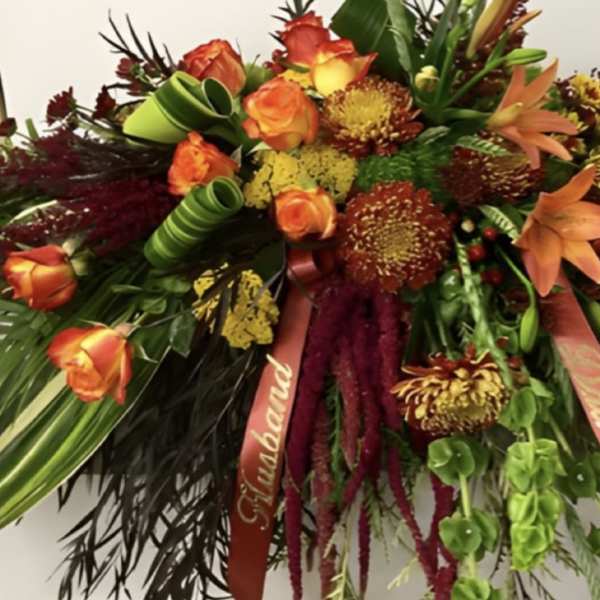 Large spray of orange roses and mixed autumn flowers with ribbons
