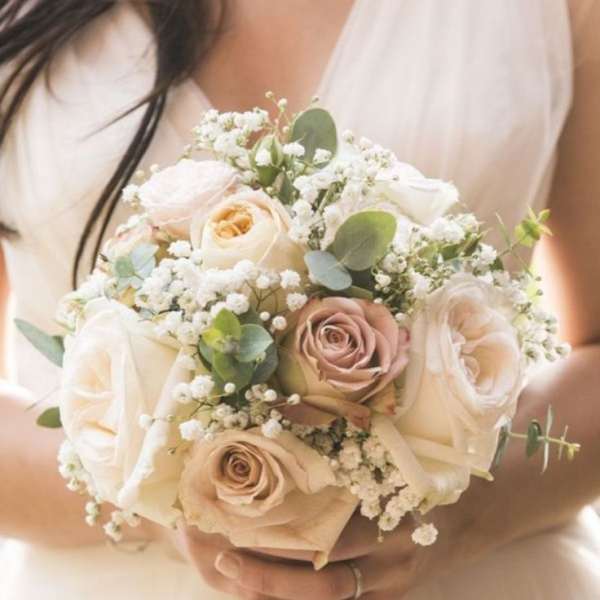 Bride holding a bouquet of blush and white roses with baby's breath