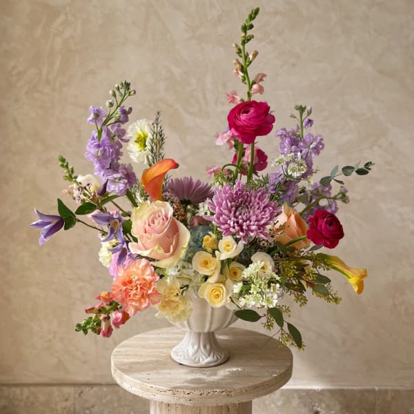 Colorful mixed flower arrangement in a white vase on a round pedestal table