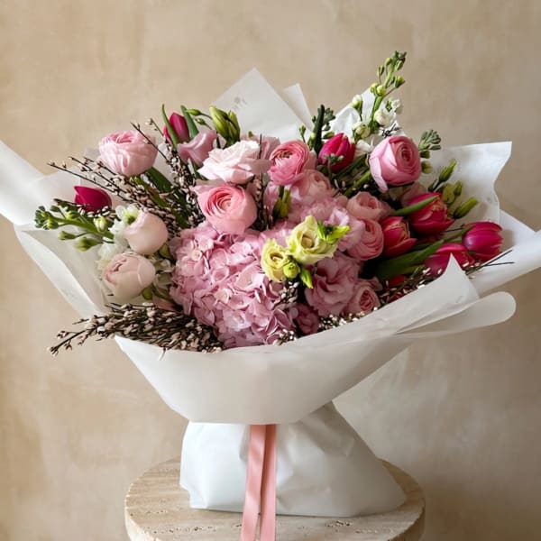 Pink mixed bouquet with roses, hydrangea, and tulips wrapped in white paper
