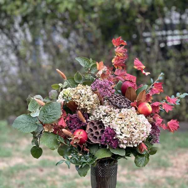 Autumn floral arrangement with hydrangeas and berries in a dark vase
