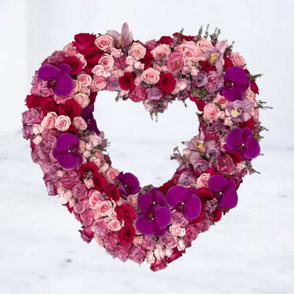 Heart-shaped floral arrangement with pink and red roses and purple orchids