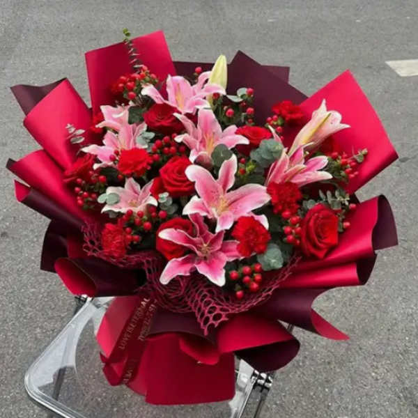 Bouquet of pink lilies and red roses wrapped in red paper