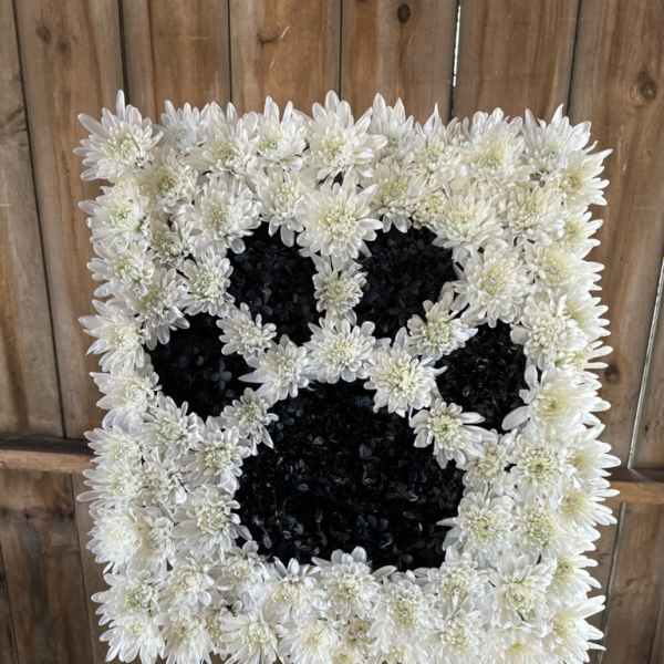 White chrysanthemum funeral wreath on an easel with a black center