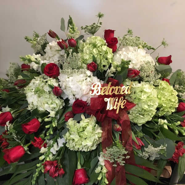 Large red and white floral spray with a ribbon and "Beloved Wife" sign