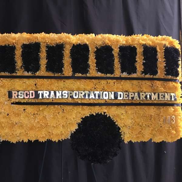 Yellow and black floral display shaped like a bus with a transportation sign