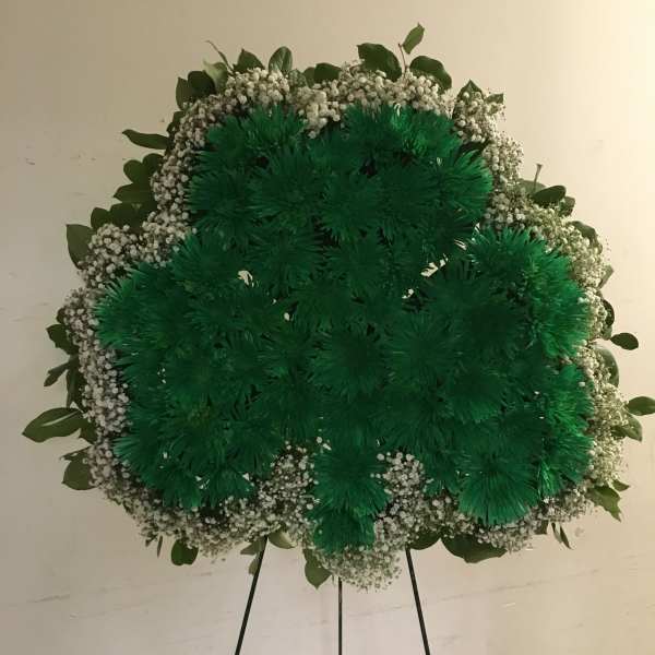 Large green floral wreath on a standing easel with white filler flowers