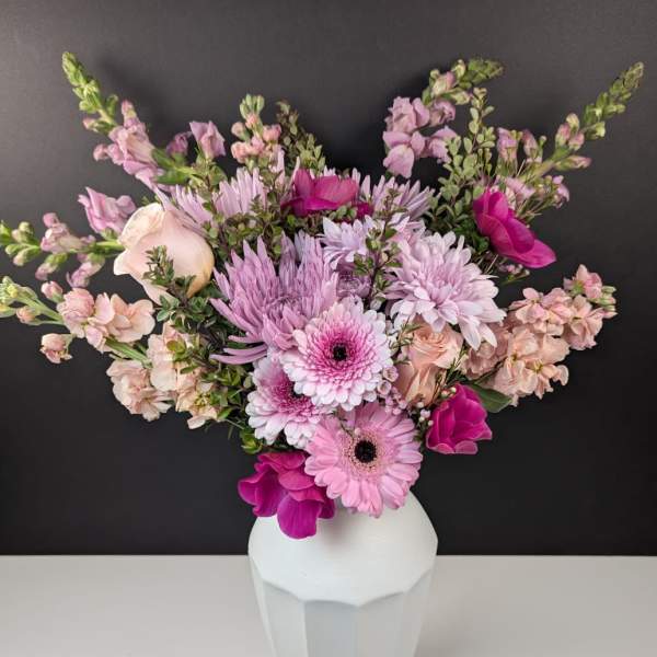 Pink and lavender flowers arranged in a white vase