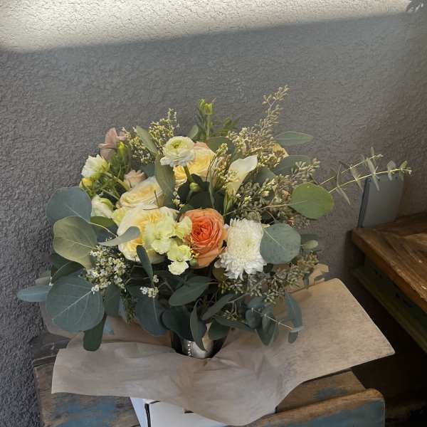 Mixed bouquet of pale roses and white blooms in a metal vase