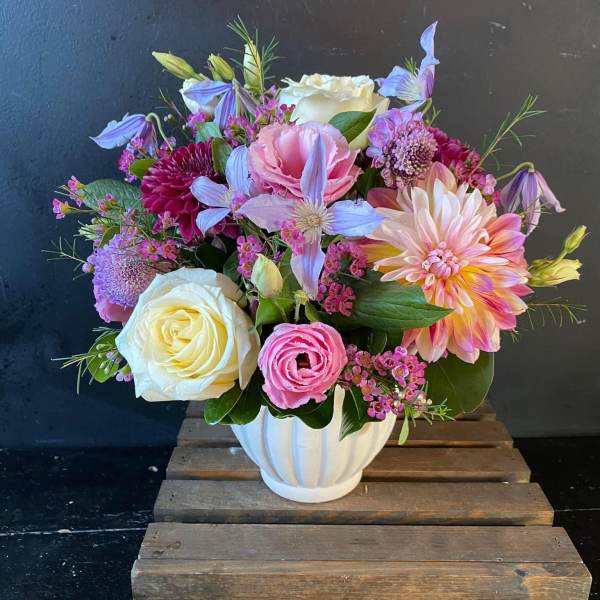 Mixed bouquet in a white vase with roses, dahlias, and pastel blooms