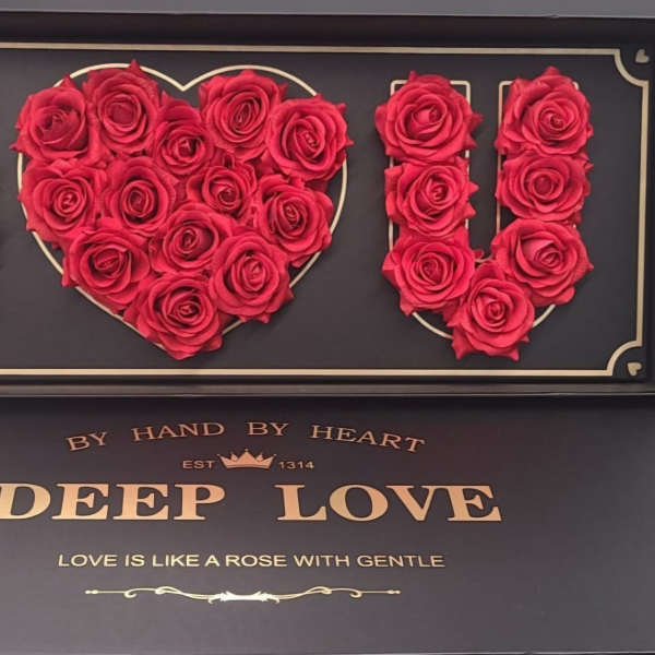 Red roses arranged to spell I heart U in a black display box