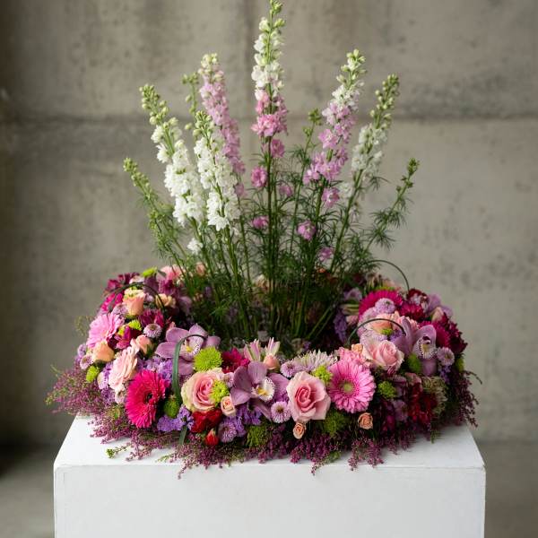 Large pink and white floral arrangement with tall spikes on a white pedestal