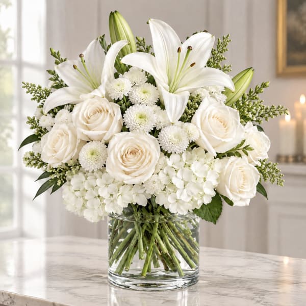 White lilies and roses arranged in a clear glass vase