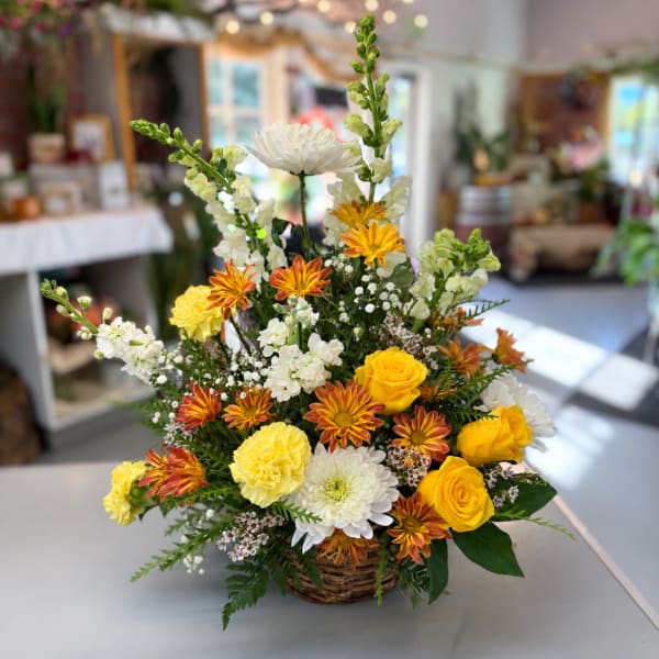 Basket arrangement of yellow roses, white mums, and orange daisies