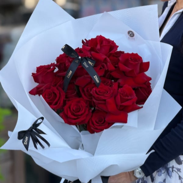 Bouquet of red roses wrapped in white paper with black ribbon