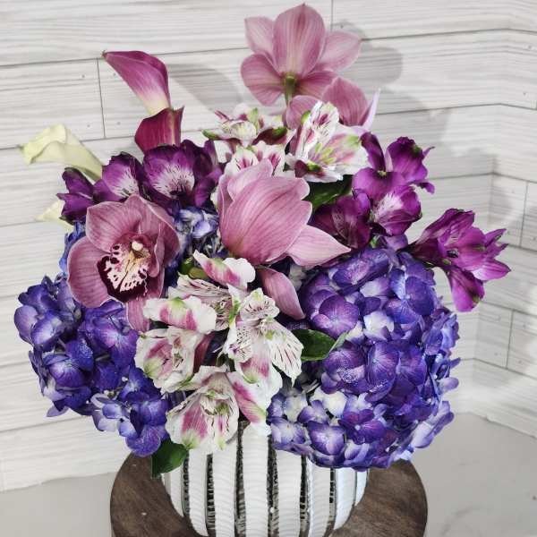 Pink and purple floral arrangement in a white vase