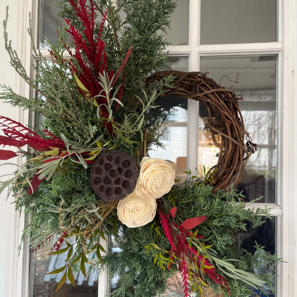 Decorative wreath with cream flowers and red foliage on a grapevine base