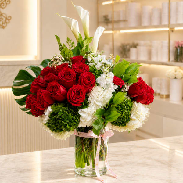 Red roses and white calla lilies in a clear glass vase