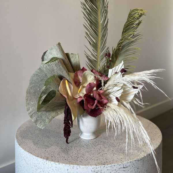 Tropical floral arrangement in a white vase with pink and cream blooms