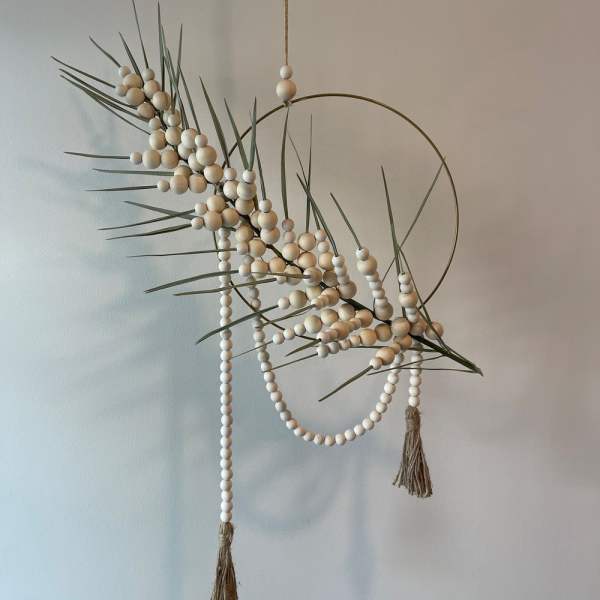 Abstract hanging wall decor with beads, grass-like stems, and a metal ring