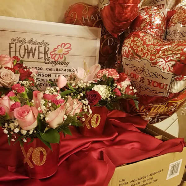 Pink and red rose arrangements in red XO containers with heart balloons