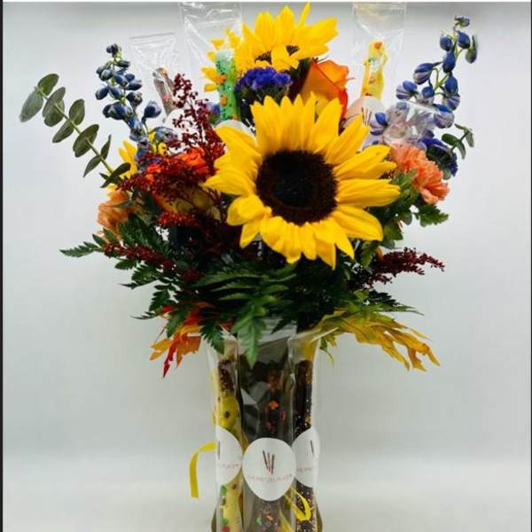 Bouquet with sunflowers, blue flowers, and orange blooms in a clear vase
