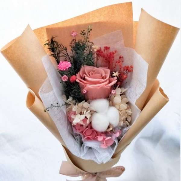 Pink rose bouquet with dried accents and cotton in brown paper
