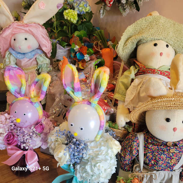 Plush bunny dolls with colorful bunny-ear balloons and flower bouquets