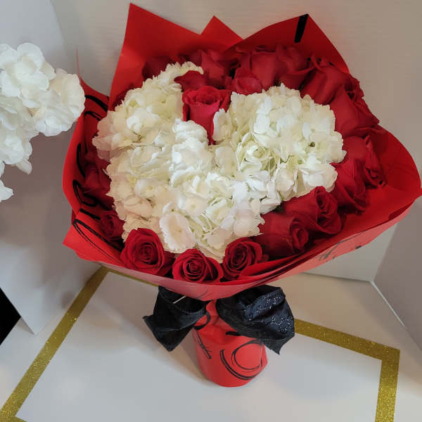 Red roses and white hydrangeas wrapped in red paper with a black ribbon
