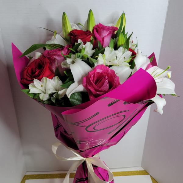Bouquet of pink and red roses with white lilies wrapped in bright pink paper