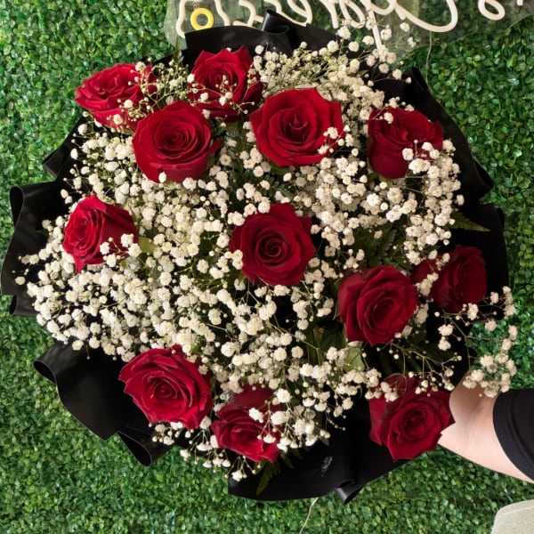 Bouquet of red roses and white baby's breath in black wrap
