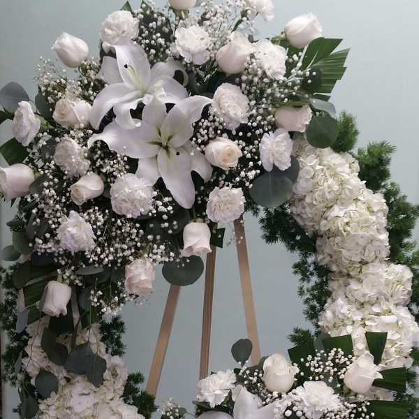 Large white floral wreath on a wooden stand