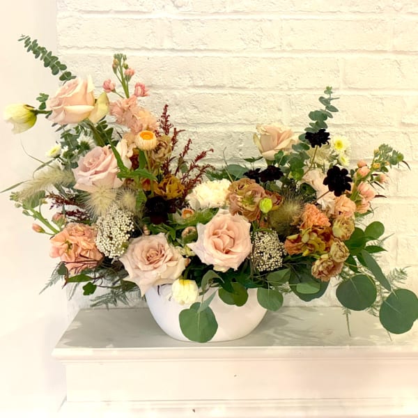 Blush roses and mixed flowers arranged in a white bowl vase