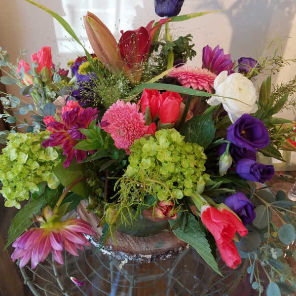 Mixed bouquet with pink, purple, white, and green flowers in a low container