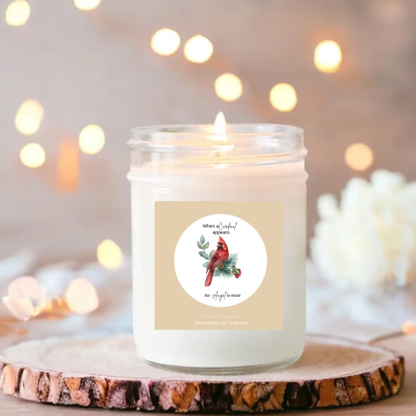 Lit scented candle in a glass jar with a cardinal label