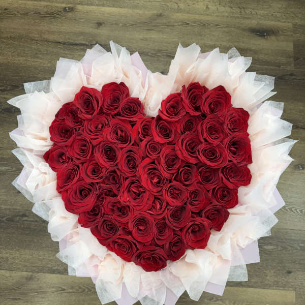 Heart-shaped bouquet of red roses wrapped in pale tissue paper